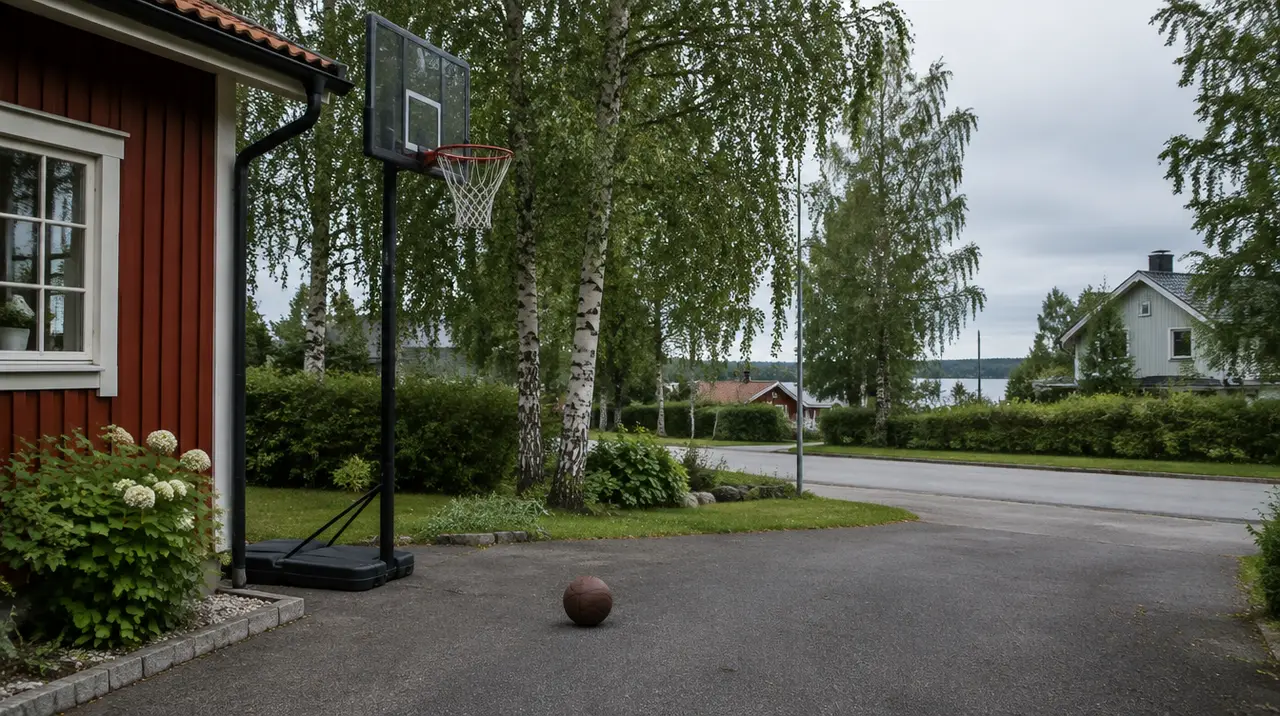 En basketkorg på en uppfart framför ett rött trähus